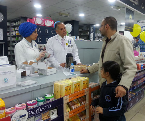 HCAC Chairman Amjad Aryan interacts with a customer at a Pharmacy One branch on Wednesday (Photo by Dana Al Emam )